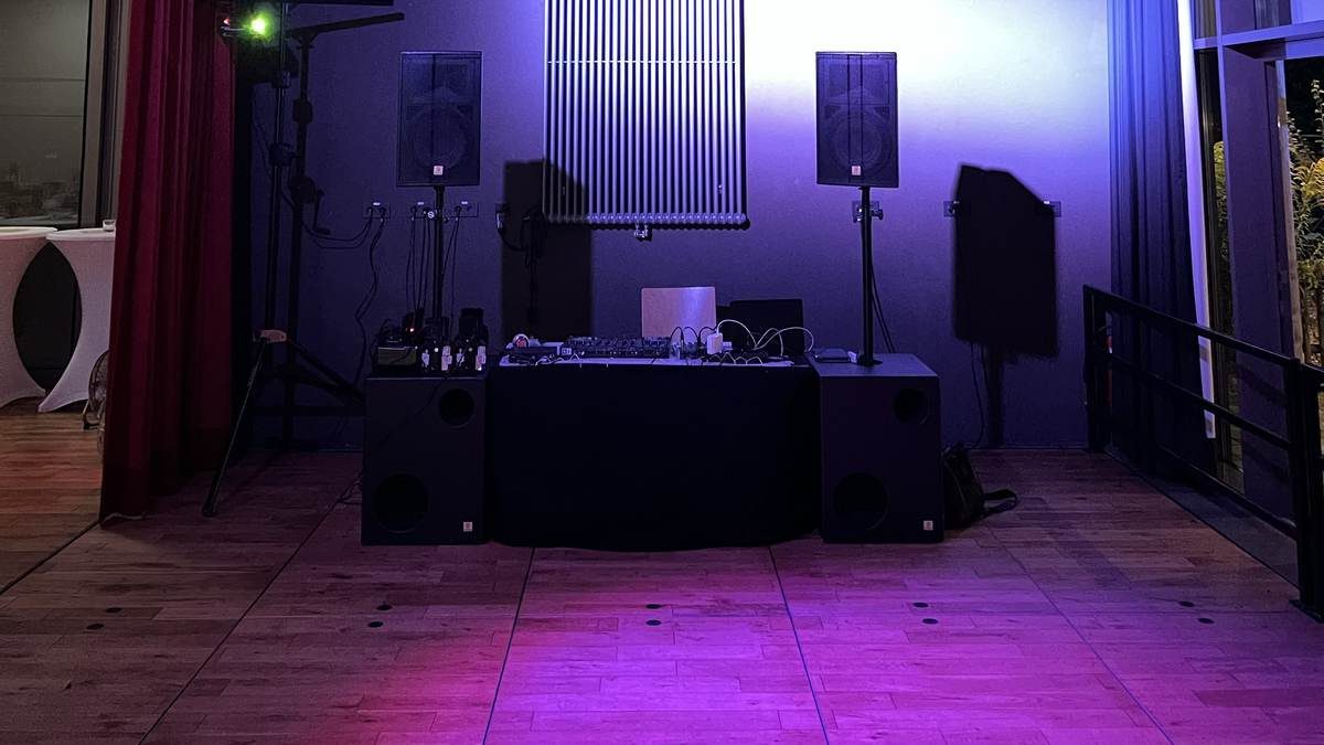 PA-Anlage mit Subwoofer und Mischpult in einem Veranstaltungsraum mit violetter Ambientebeleuchtung