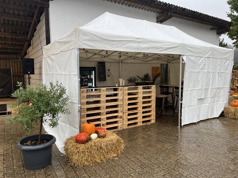 Scherenzelt mit Palettenbar, Heuballen und Kürbisdeko auf einem Bauernhof
